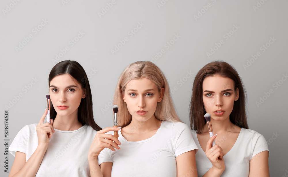 Beautiful young women applying makeup on light background