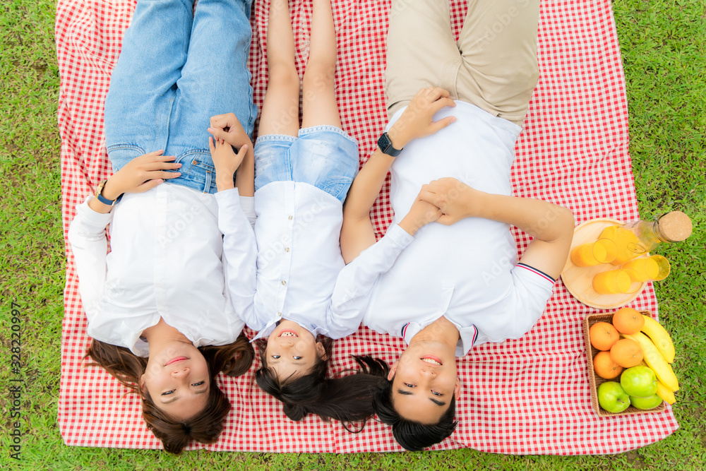 Asian teen family happy holiday picnic moment in the park with father, mother and daughter lying on 