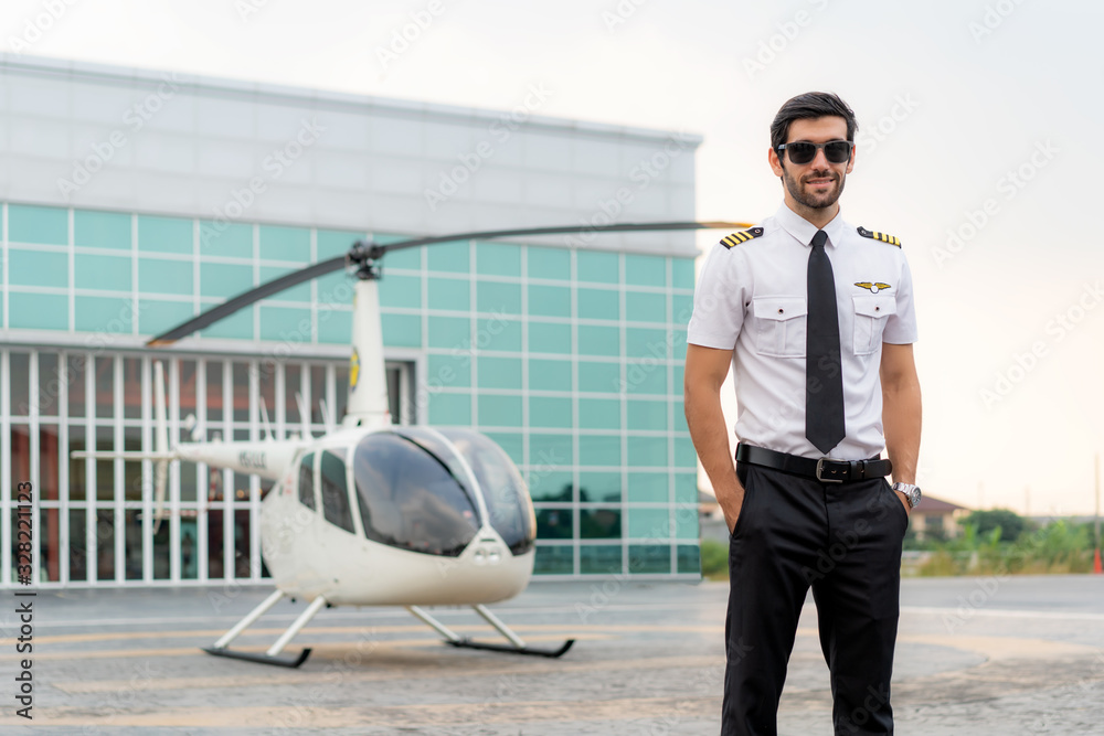 Portrait of handsome commercial pilot in captain white uniform standing and looking smart near small