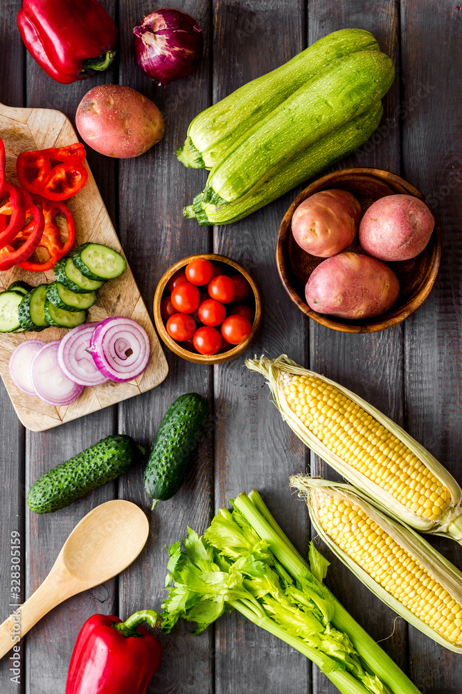 Autumn harvest. Vegetables - potato,cucumber, corn, greenery - on dark wooden background top-down