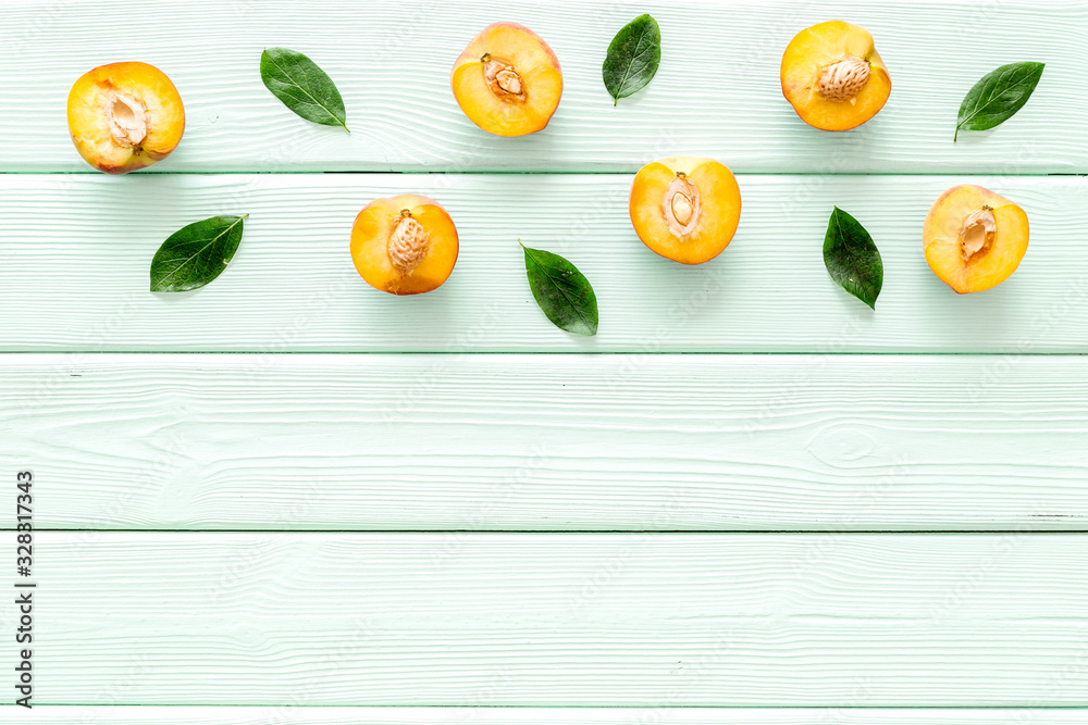 Peach slices and leaves pattern on green wooden background top-down copy space frame