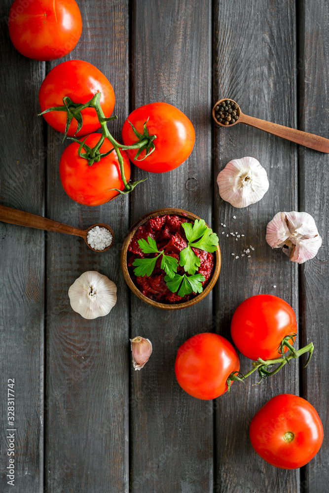 Homemade tomato sause near ingredients - garlic, spices - on dark wooden background top-down