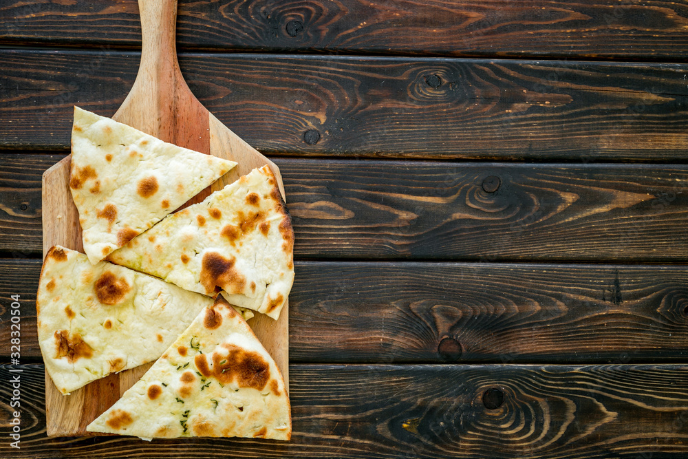 Make focaccia. Traditional italian bread on cutting board on dark wooden table top-down copy space