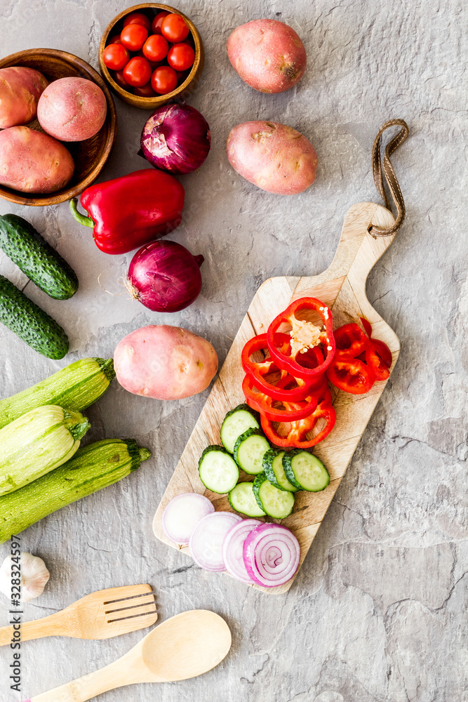 Autumn harvest. Vegetables - potato,cucumber, corn, greenery - on light stone background top-down