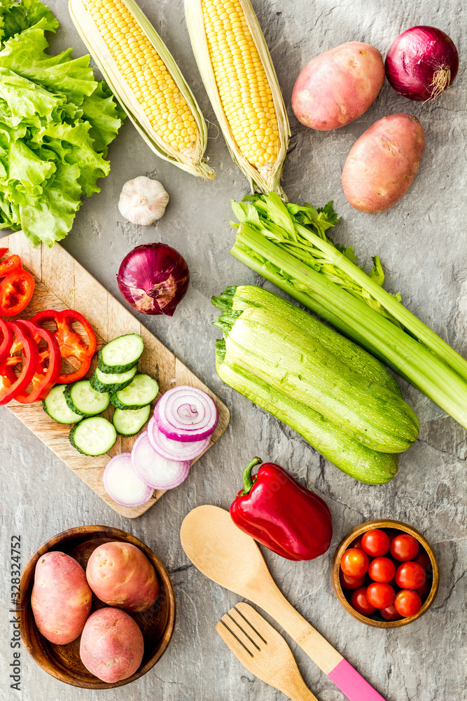 Autumn harvest. Vegetables - potato,cucumber, corn, greenery - on light stone background top-down