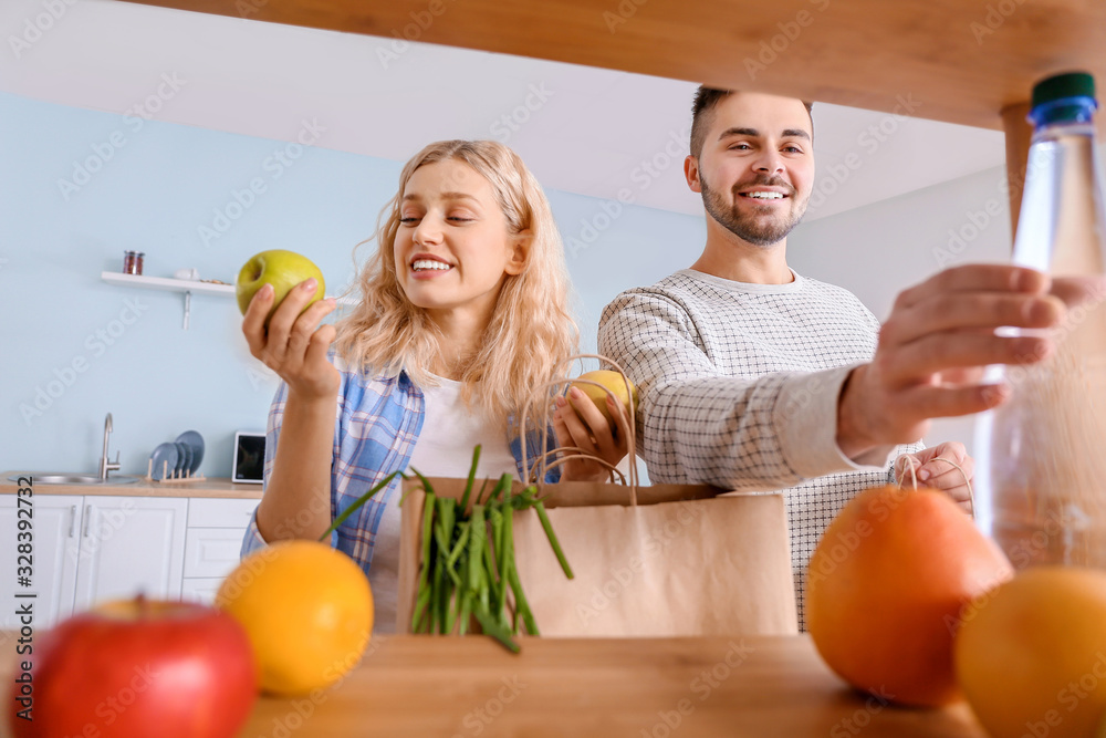 Couple unpacking fresh products from market in kitchen