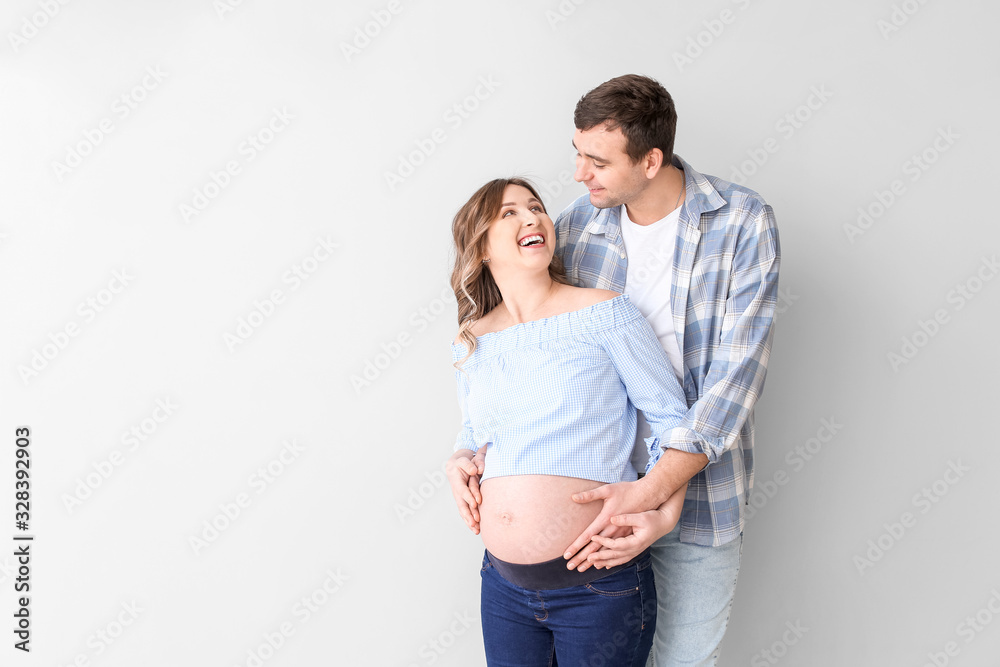 Beautiful pregnant couple on grey background