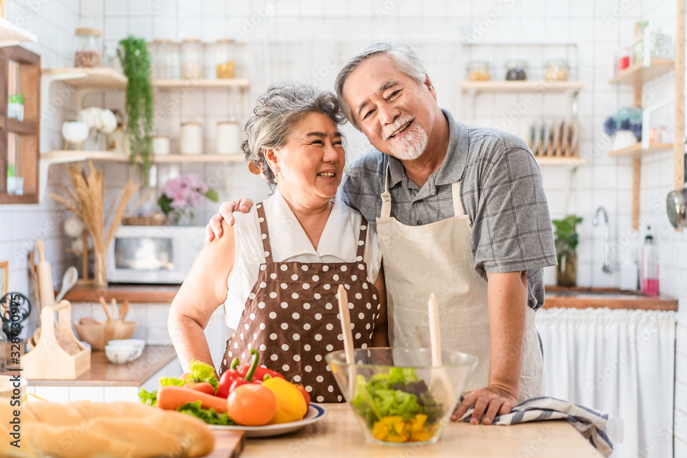 Couple senior Asian elder happy living in home kitchen. Grandfather cooking salad dish with grandmot