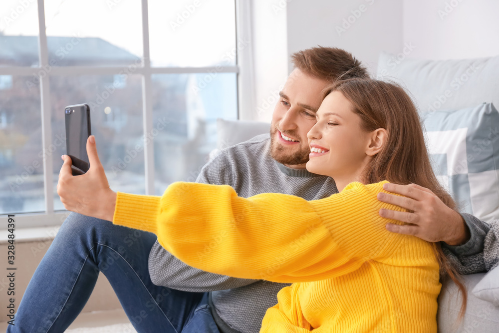 Happy young couple taking selfie at home