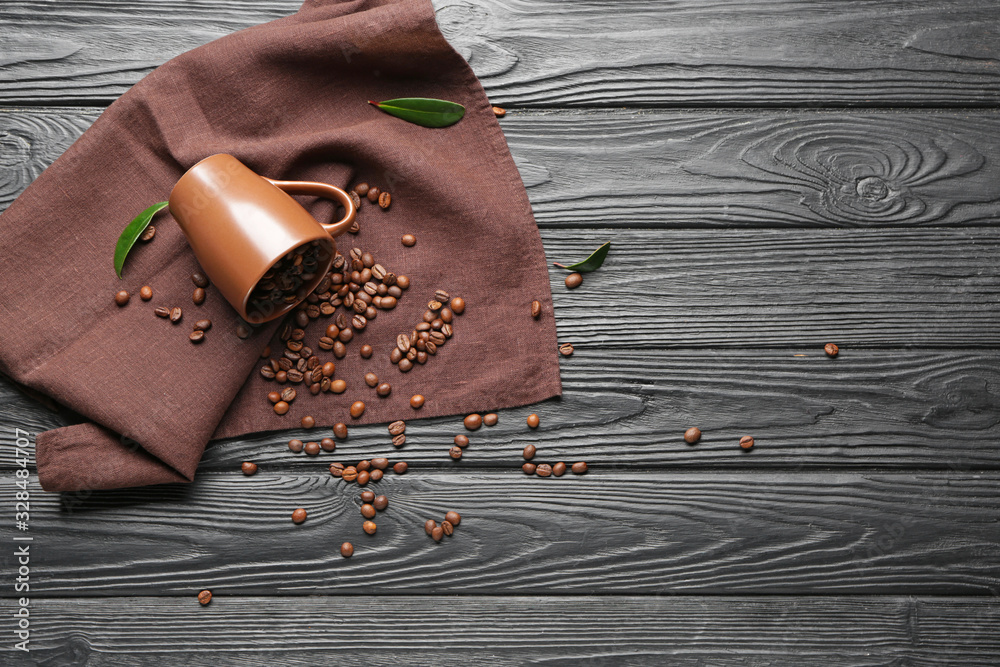 Overturned cup with coffee beans on table