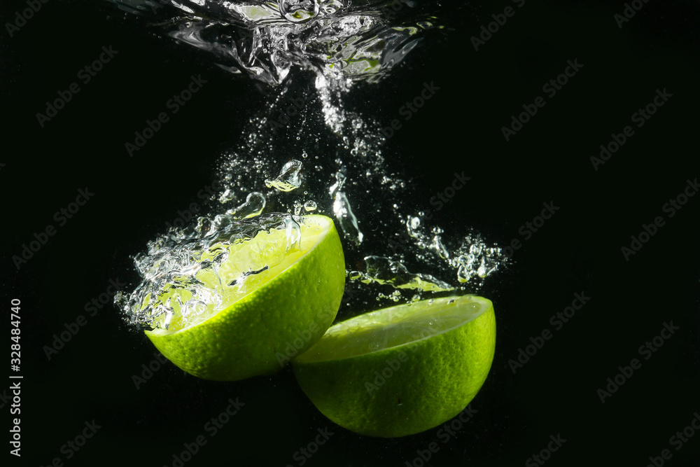 Falling of cut lime into water against dark background