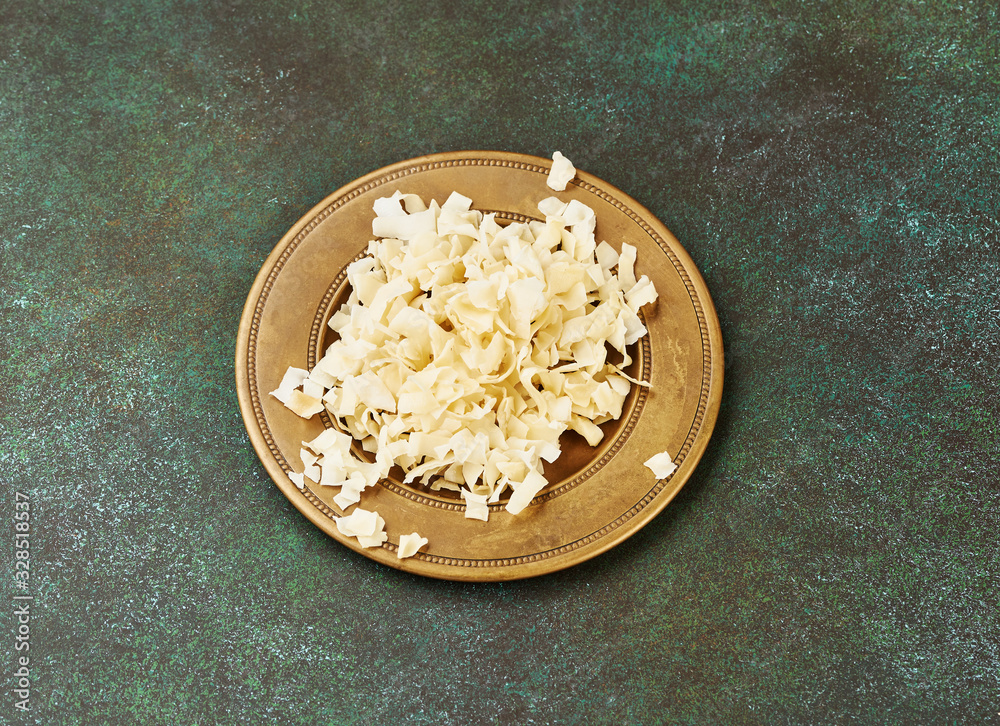 Organic Roasted coconut chips in a arabic plate on a green background.