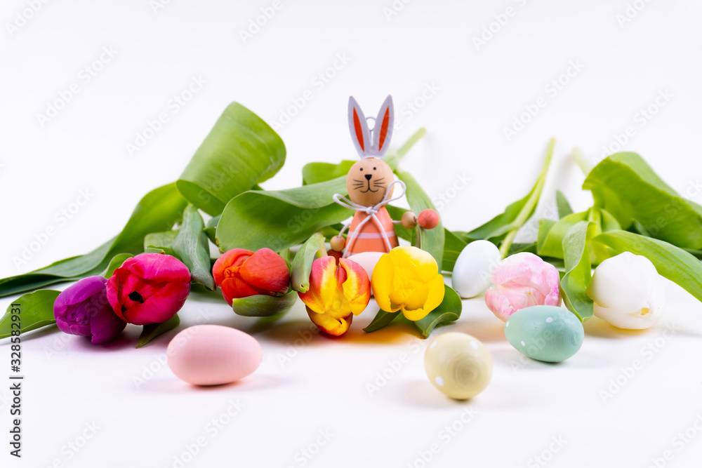 Colorful tulips laying in a row with a easter bunny on white background with copy space