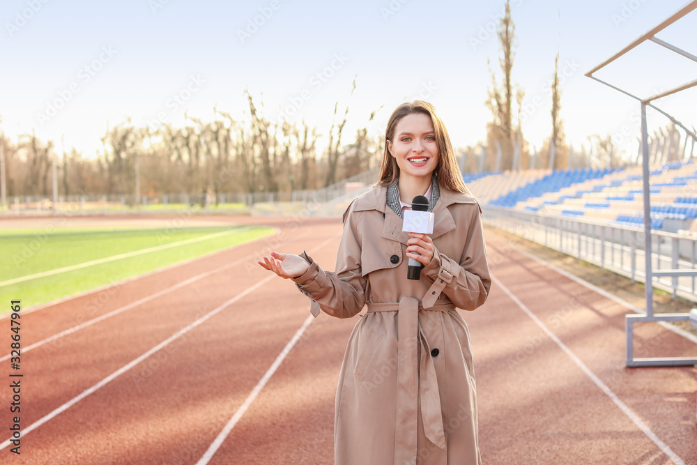 Beautiful reporter with microphone at the stadium