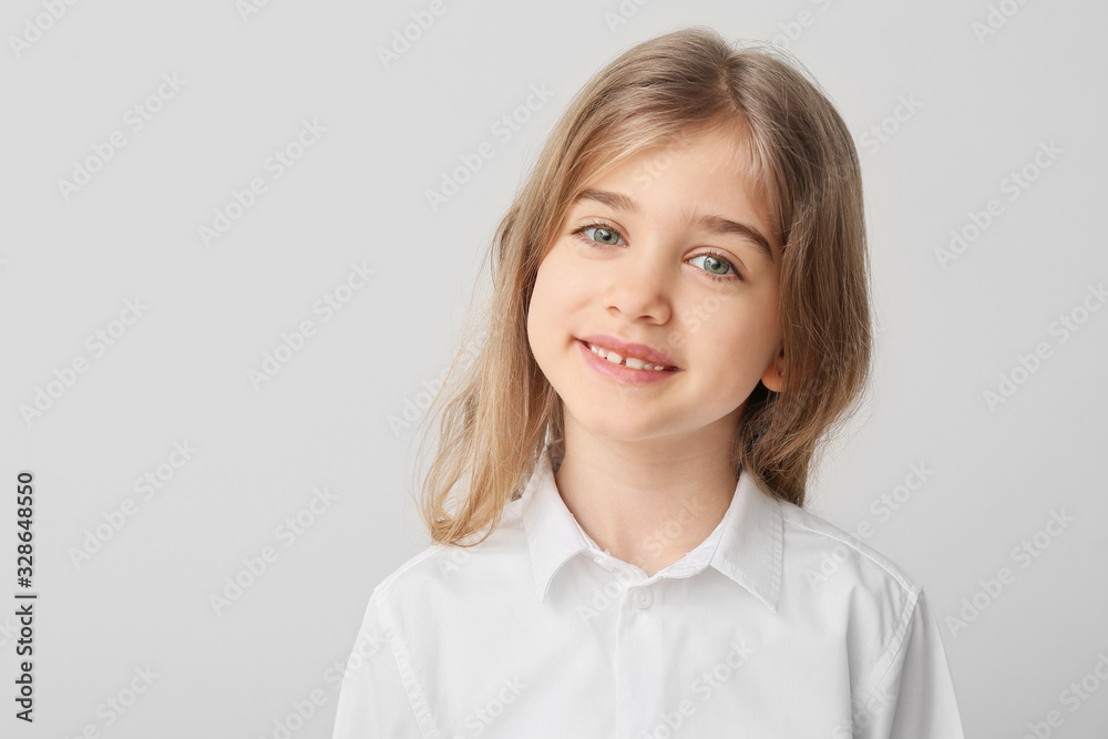 Happy little girl with healthy teeth on light background