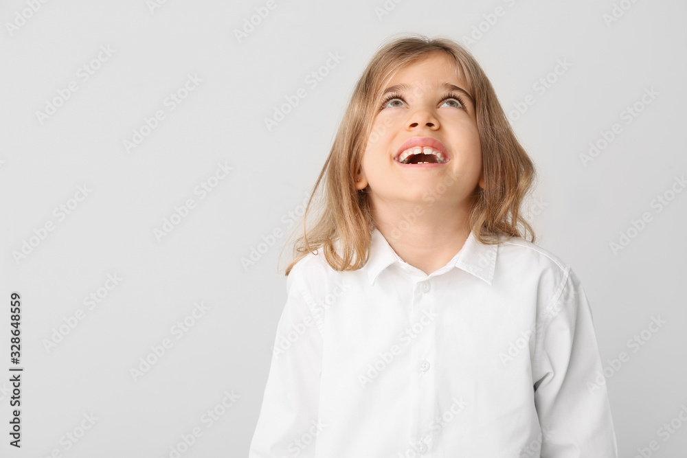 Happy little girl with healthy teeth on light background