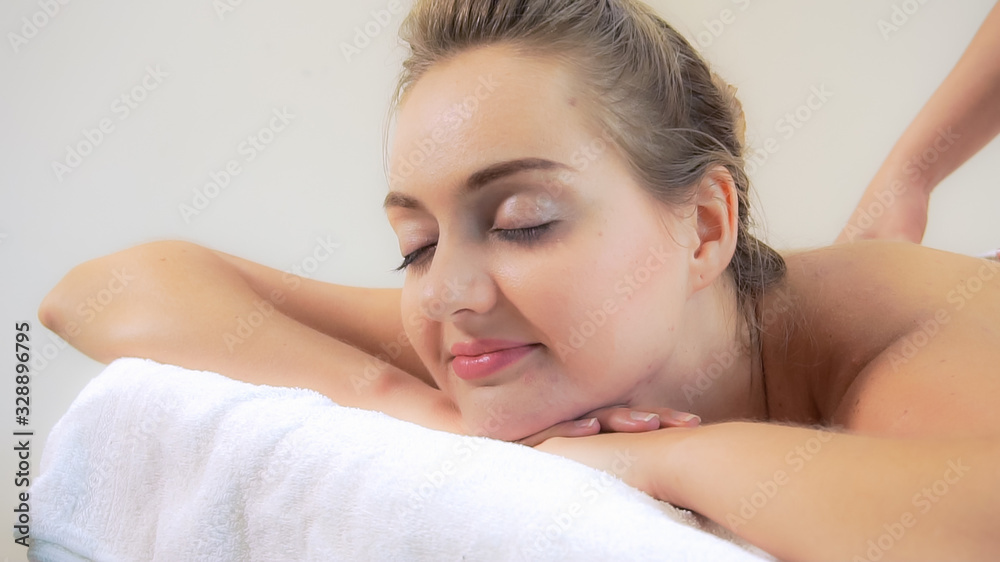 Relaxed woman getting back massage in luxury spa with professional massage therapist. Wellness, heal