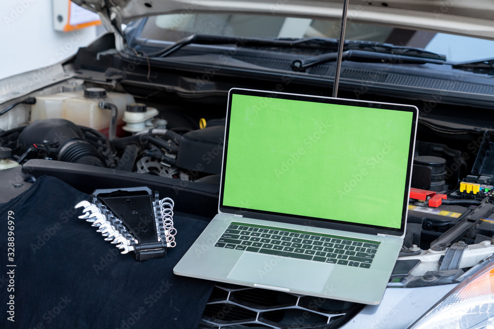 Laptop computer on car hood for engine diagnostic. Car garage repair service concept.