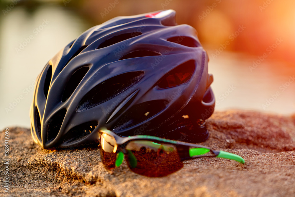 Bicycle helmet and bike glasses on the street, rock with blurred background.