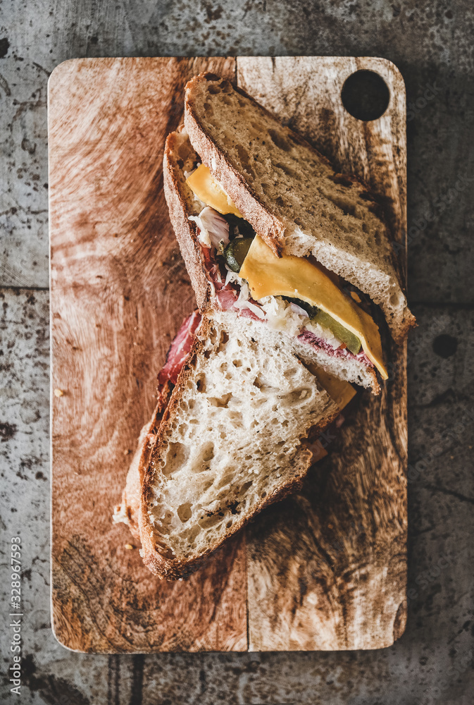 Flat-lay of big Ruben pastrami sandwich slices in sourdough bread with cheese, pastrami, sauer kraut