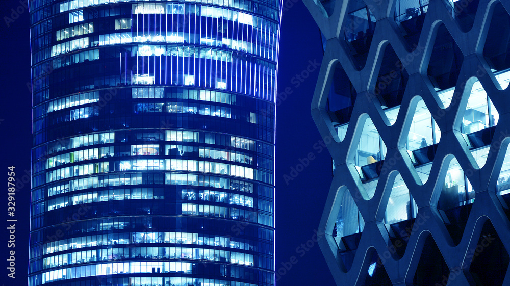 Night architecture - building with glass facade.Blue color of night lights. Modern building in  busi