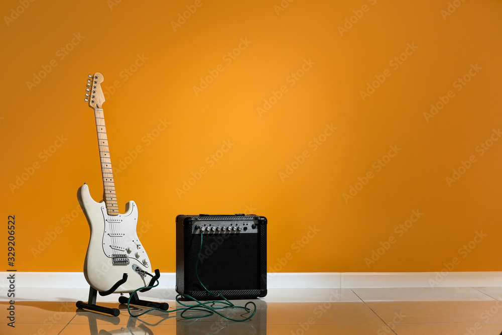 Modern guitar and amplifier near color wall