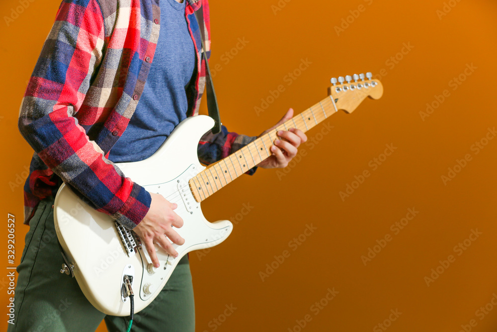 Young man playing guitar on color background