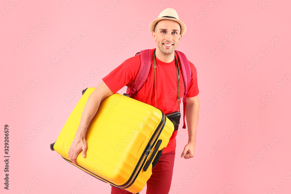 Male tourist with luggage on color background