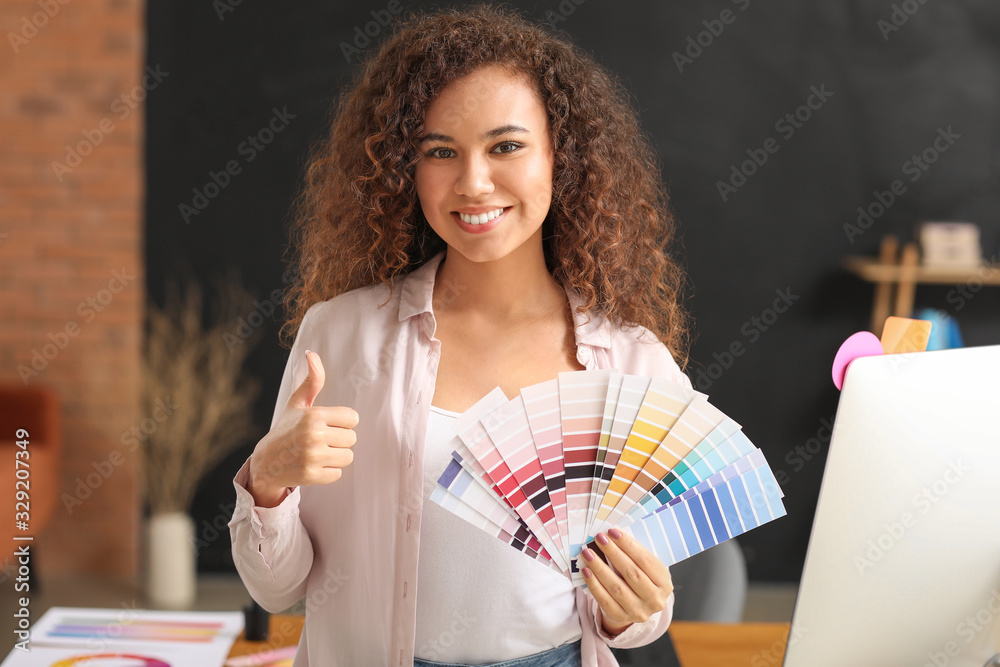 African-American designer with color palettes showing thumb-up in office