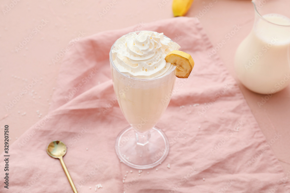 Glass of tasty banana milkshake on color background