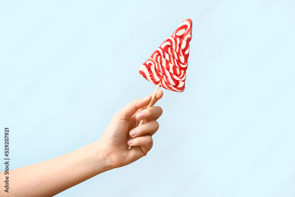 Female hand with sweet lollipop on light background