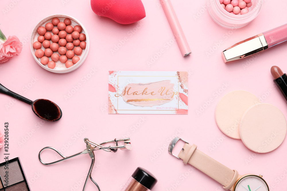 Decorative cosmetics and accessories with business card of makeup artist on color background