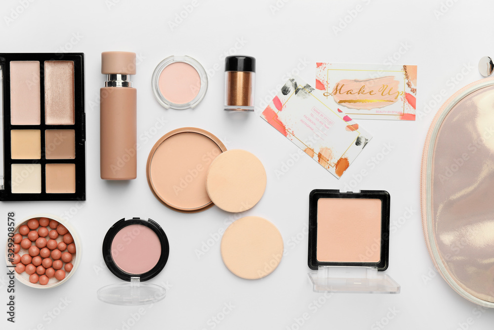 Decorative cosmetics with business cards of makeup artist on white background