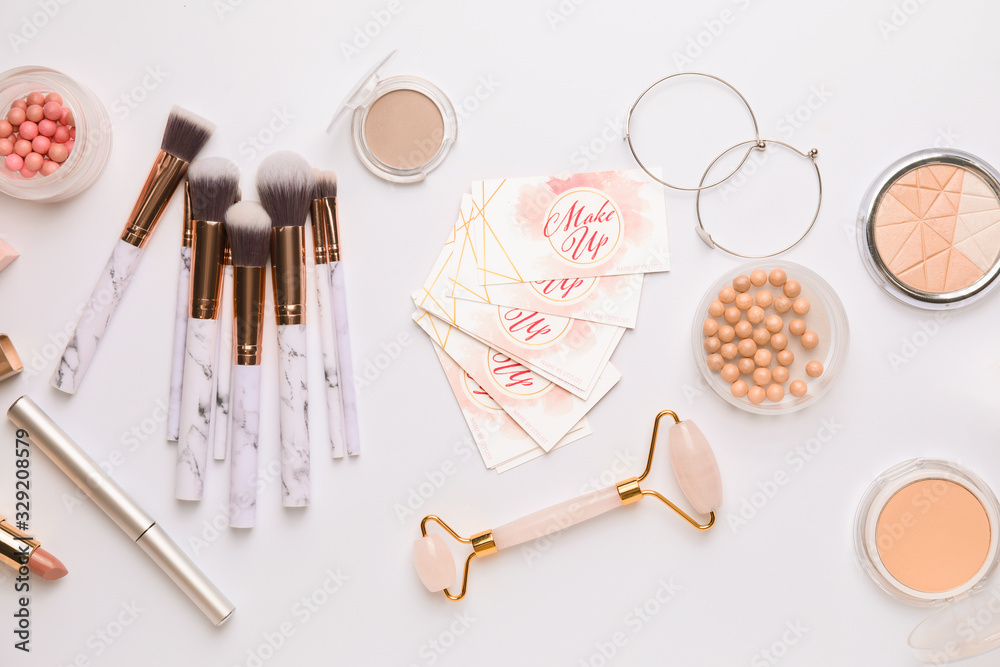 Decorative cosmetics and accessories with business cards of makeup artist on white background