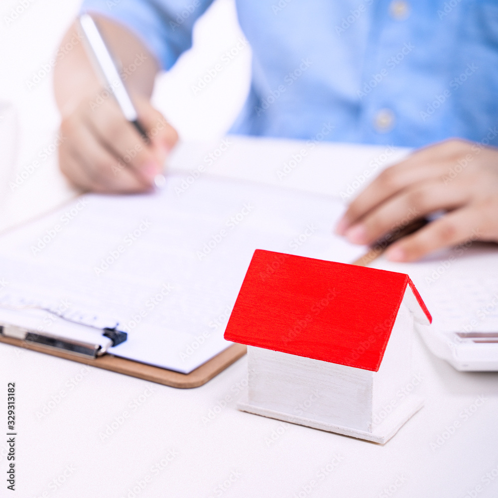 Business concept - Young Asian man in blue shirt calculates, signs agreement contract to buy a house