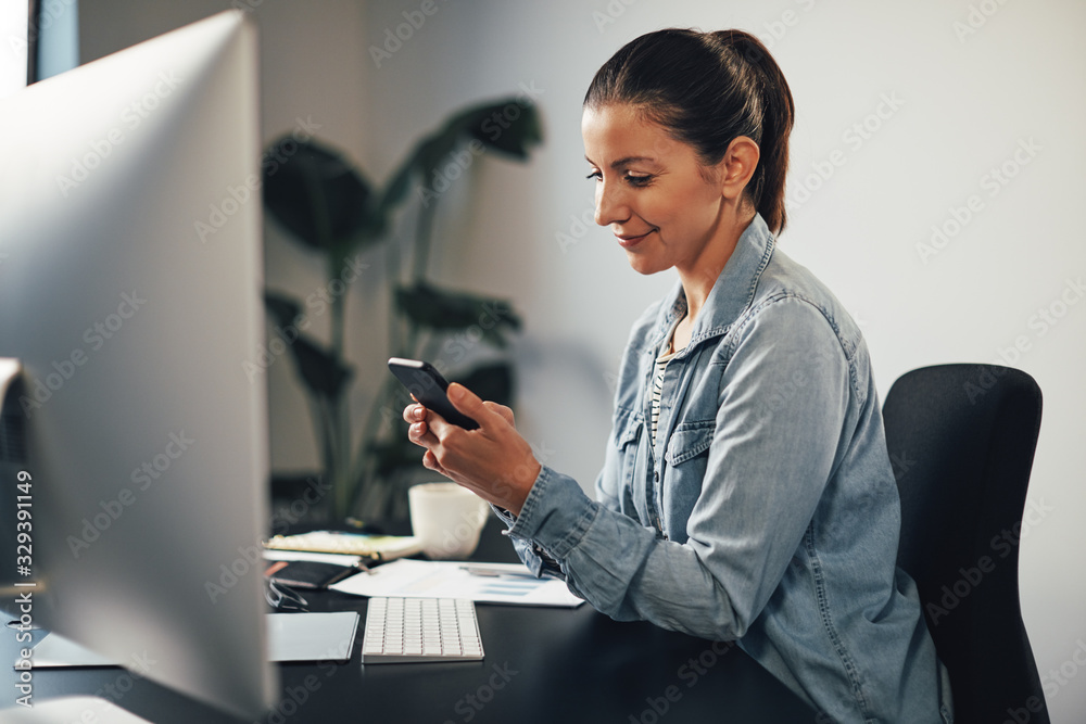 Smiling businesswoman sending a text message on her cellphone