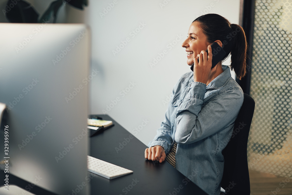 Smiling businesswoman talking on her cellphone at her office des