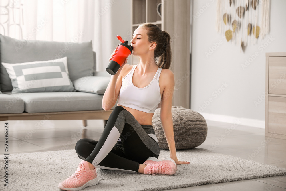 Sporty young woman with protein shake at home