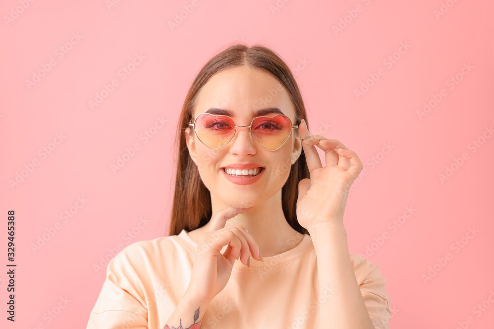 Young woman with stylish sunglasses on color background