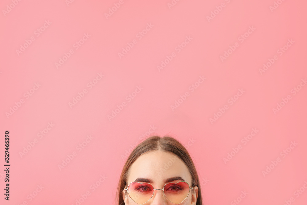 Young woman with stylish sunglasses on color background