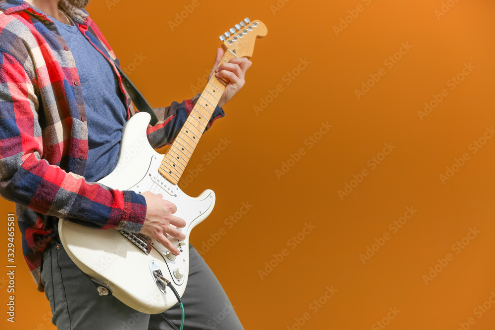 Young man playing guitar on color background