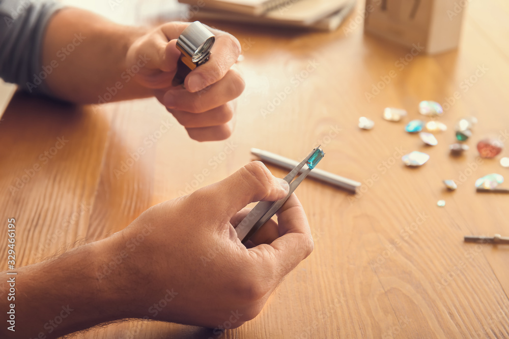 Jeweler examining gemstone in workshop, closeup