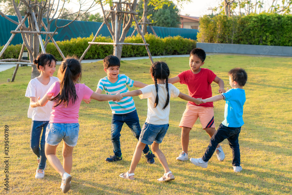 Large group of happy Asian smiling kindergarten kids friends holding hands playing and dancing play 