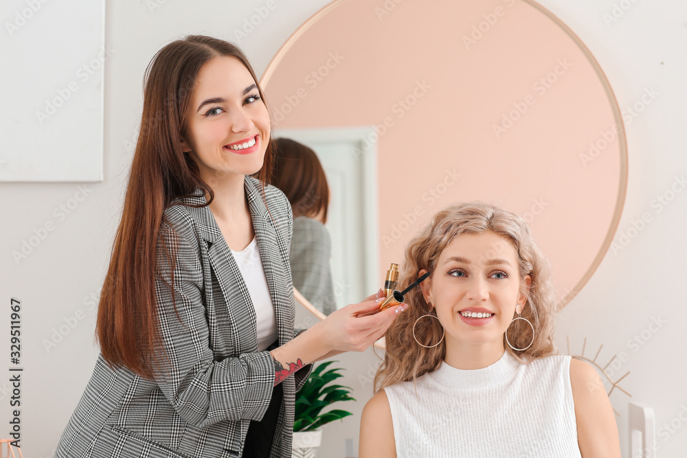 Professional makeup artist working with young woman in salon