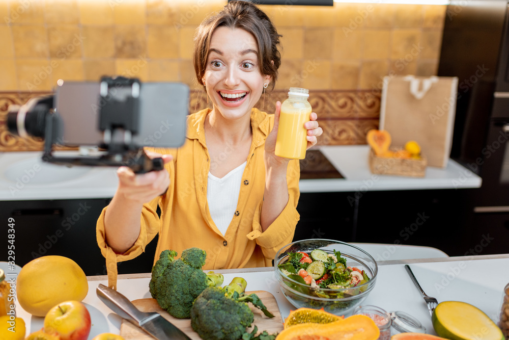 Young and cheerful woman vlogging on mobile phone about healthy food and cooking. Concept of healthy