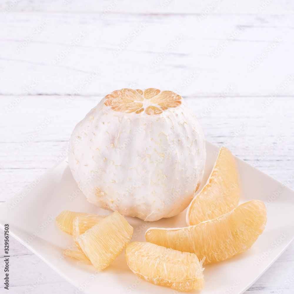 Fresh peeled pomelo, pummelo, grapefruit, shaddock on bright wooden table background. Seasonal fruit