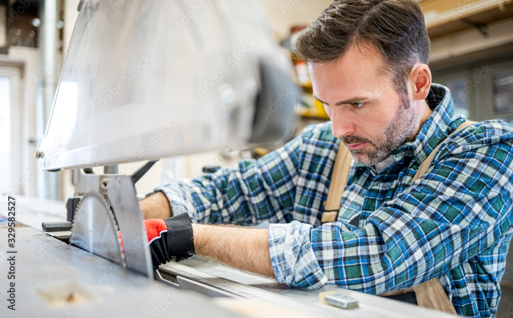 Mechanic repairs the circular saw machine and putting blade in carpentry workshop