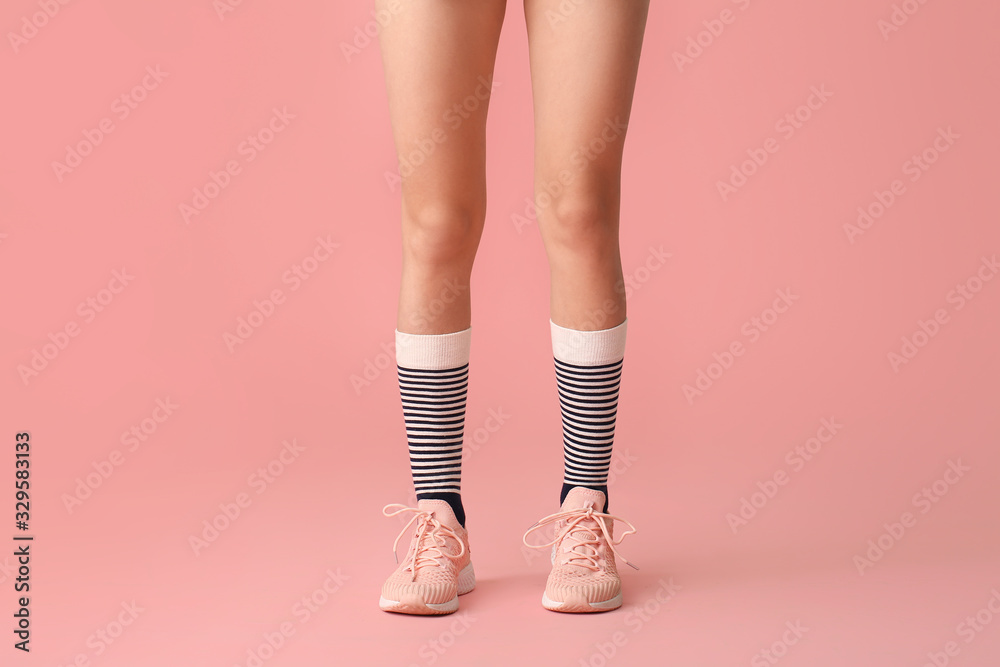 Legs of young woman in socks and shoes on color background