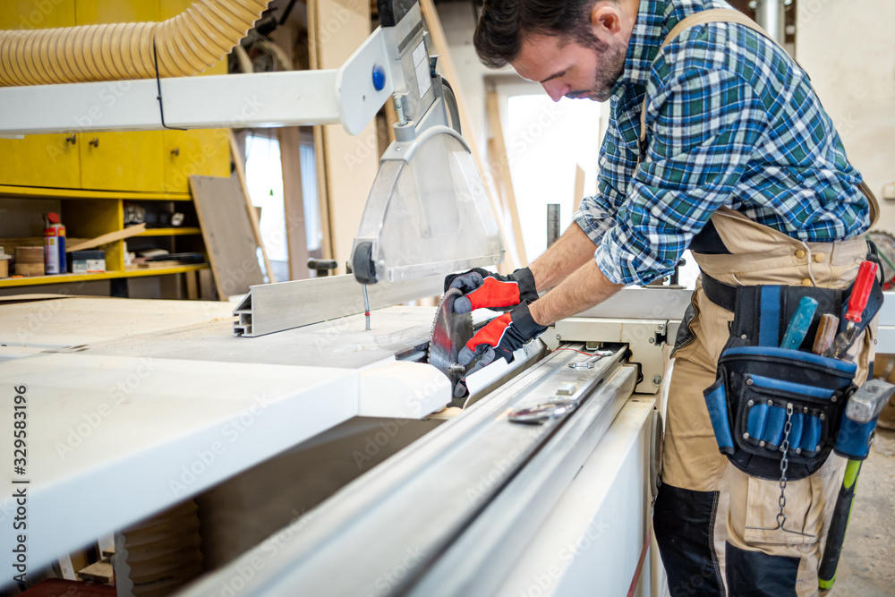 Mechanic repairs the circular saw machine and putting blade in carpentry workshop