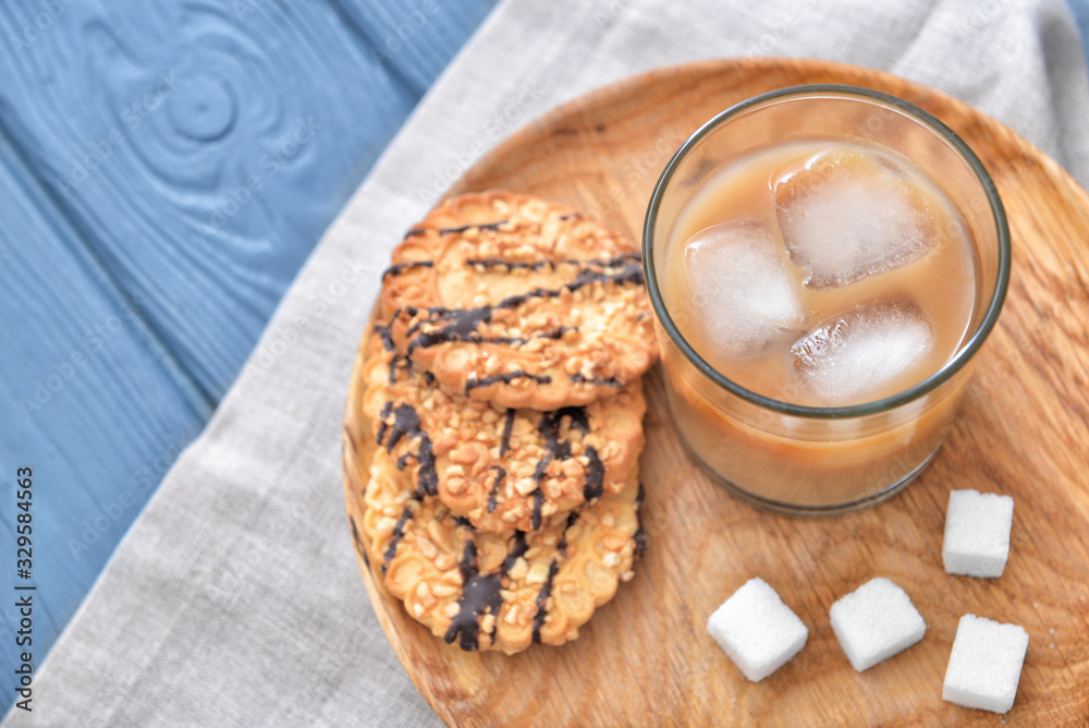 Glass of tasty iced coffee with cookies on table